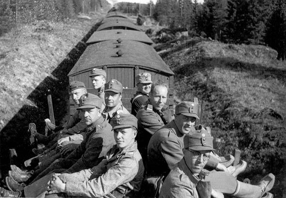 Juna kulkee metsn reunustamaa rataa, ja sen katolla istuu miehi.